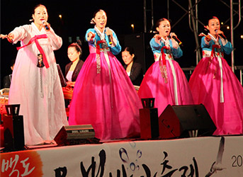 분홍빛 치마와 푸른빛 한복저고리를 입은 여인들이 무대위에서 공연을 펼치는 모습