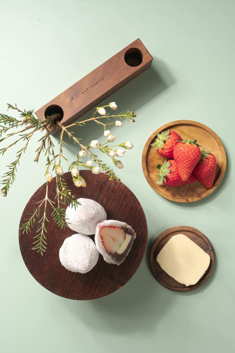 찹쌀떡과 딸기가 나무 접시에 담겨있고 주변에 장식품이 놓여 있는 사진