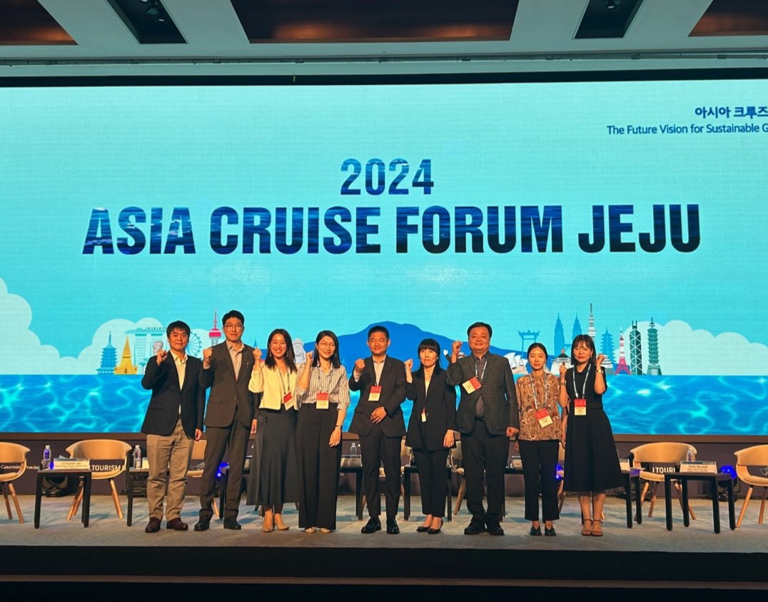 2024 ASIA CRUISE FORUM JEJU 라는 대형 화면 앞에서 여러 명의 사람들이 단체 사진을 찍고 있는 모습