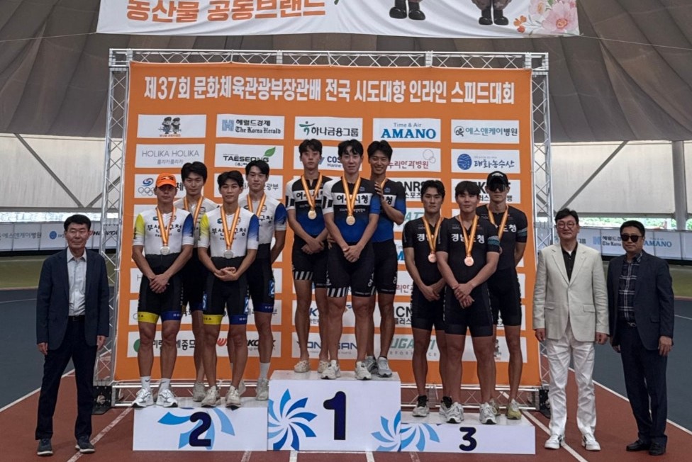 인라인 스피드대회에서 메달을 수상한 선수들이 시상대에 서 있다. 왼쪽에는 관계자가 있으며, 오른쪽에는 관중이 있다.