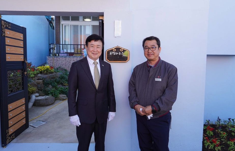 여수시 시장과 관계자가 ‘희망하우스 29호’ 현판 앞에서 기념촬영을 하고 있는 모습. 흰색 외벽과 정갈하게 꾸며진 마당이 보이며, 벽면에는 ‘희망하우스 29호’ 현판이 걸려 있다