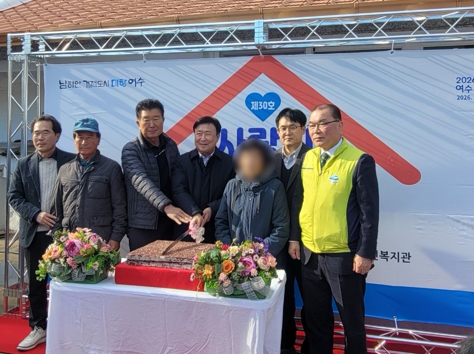 여수시장을 비롯한 롯데케미칼·지역 기관 관계자들이 화양면 ‘희망하우스 30호’ 준공 현판식에서 어르신과 함께 떡를 자르는 장면