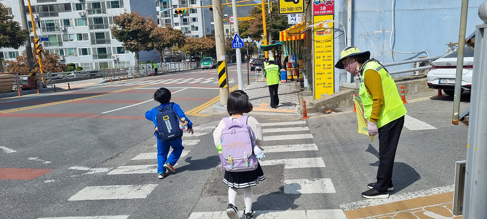 ▲ 등하굣길 안전지킴이의 교통안내 지도에 따라 학생들이 안전하게 하교하고 있다.    (죽림초등학교 인근)