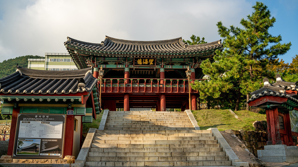 전통 한옥 스타일의 건물이 계단 위에 위치하고 있으며, 건물 앞에는 공사 안내판이 세워져 있다.