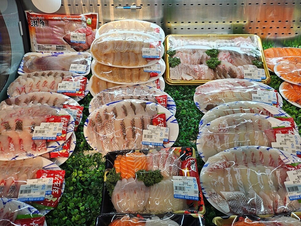 다양한 종류의 포장된 생선이 진열된 수산물 코너의 모습으로 가격이 표시되어 있다.