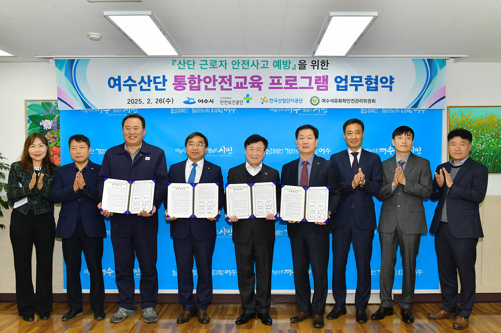 여수에서 여수산단 통합안전교육 프로그램 업무협약을 체결하는 장면으로, 여러 관계자들이 서명된 문서를 들고 기념사진을 찍고 있다.