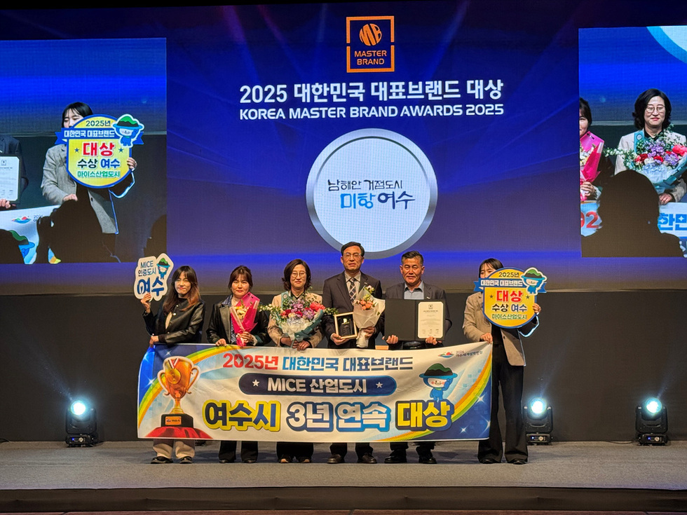 2025 대한민국 대표브랜드 시상식에서 여수시가 MICE 산업도시 부문에서 3년 연속 대상을 수상하고 있다. 수상자들이 상패와 기념품을 들고 기념사진을 찍고 있다.