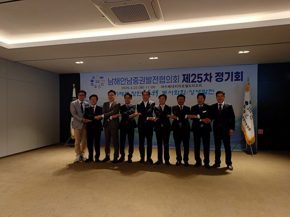 남해안남중권발전협의회 제25차 정기회가 여수베네치아호텔에서 열리고 있으며, 참석자들이 손을 맞잡고 있다.