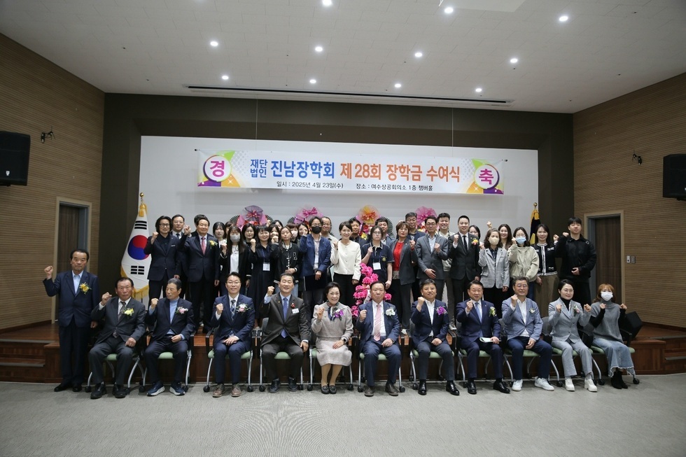 진남장학회 제 28회 장학금 수여식에서 참석자들이 기념사진을 찍고 있다. 행사에는 여러 명의 참석자가 있으며, 배경에는 행사 정보가 적힌 현수막이 걸려 있다.