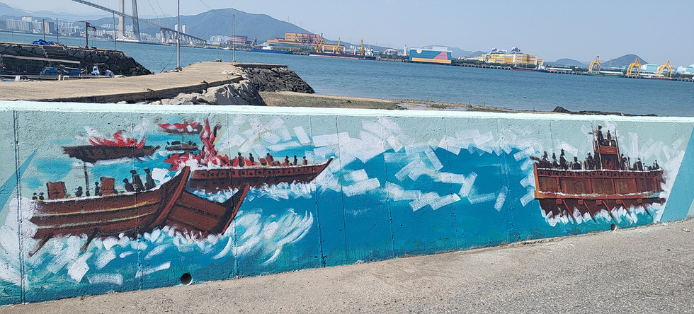해안가에 그려진 벽화로, 두 척의 배가 바다를 항해하는 모습이 담겨 있다. 배 주변에는 파도가 일고 있으며, 배 위에는 사람들의 실루엣이 보인다.
