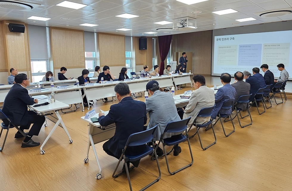 회의실에서 여러 사람들이 앉아 회의 중이며, 한 사람이 발표를 하고 있다. 화면에는 문화 인프라 구축에 대한 내용이 표시되고 있다.