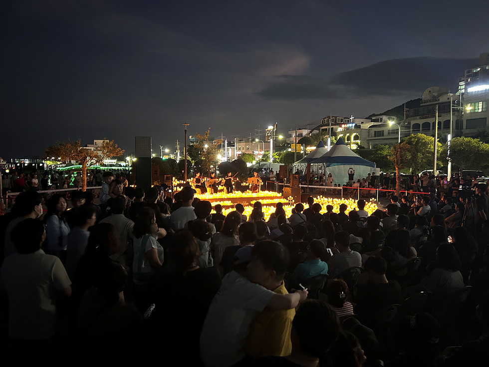 여수 소호동동다리 대광장에서 열린 캔들라이트 콘서트 현장, 수많은 관객이 촛불이 밝혀진 무대를 둘러싸고 공연을 관람하는 모습