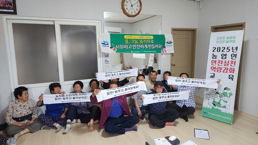 농업인들이 안전 교육을 위해 모여 농작물 안전재해 제로를 외치며 현수막을 들고 있는 모습이다.