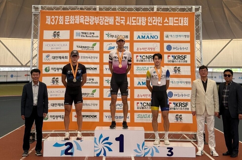 인라인 스피드대회 시상식에서 1위, 2위, 3위 선수들이 메달을 목에 걸고 포즈를 취하고 있으며, 왼쪽에는 관계자들이 서 있다.