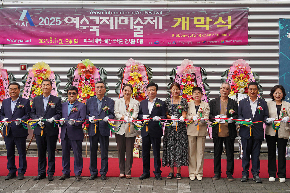 여수국제미술제 개막식에서 여러 인사들이 리본을 자르고 있다. 배경에는 개막식 관련 현수막과 꽃다발이 보인다.
