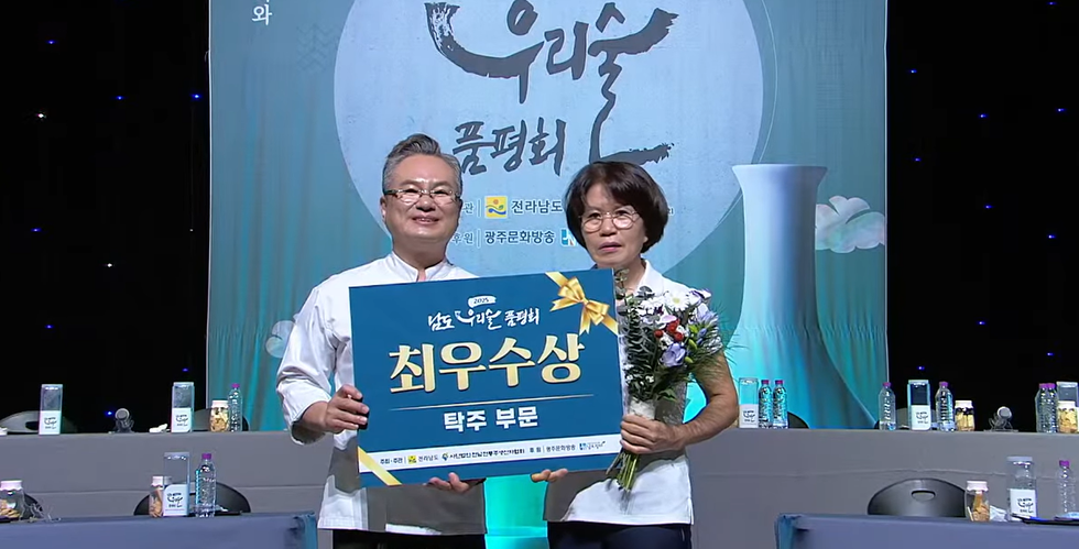 2023 우리술 품평회에서 최우수상을 수상한 두 사람이 상패와 꽃다발을 들고 기념사진을 찍고 있다.