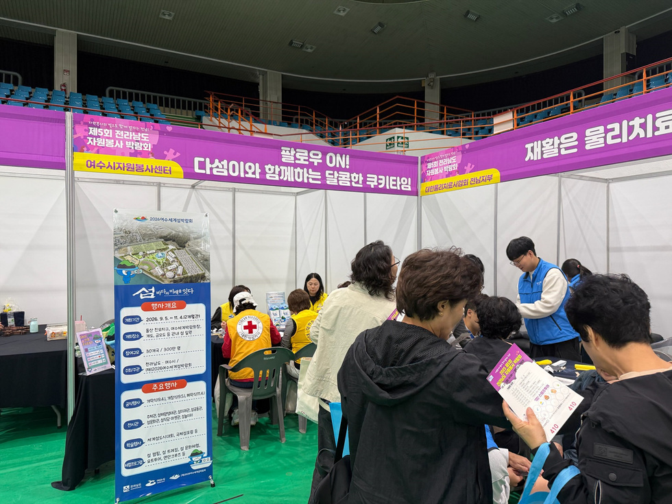 여수시자원봉사센터 부스에서 자원봉사자들과 관람객들이 쿠키 만들기 체험을 하고 있는 장면