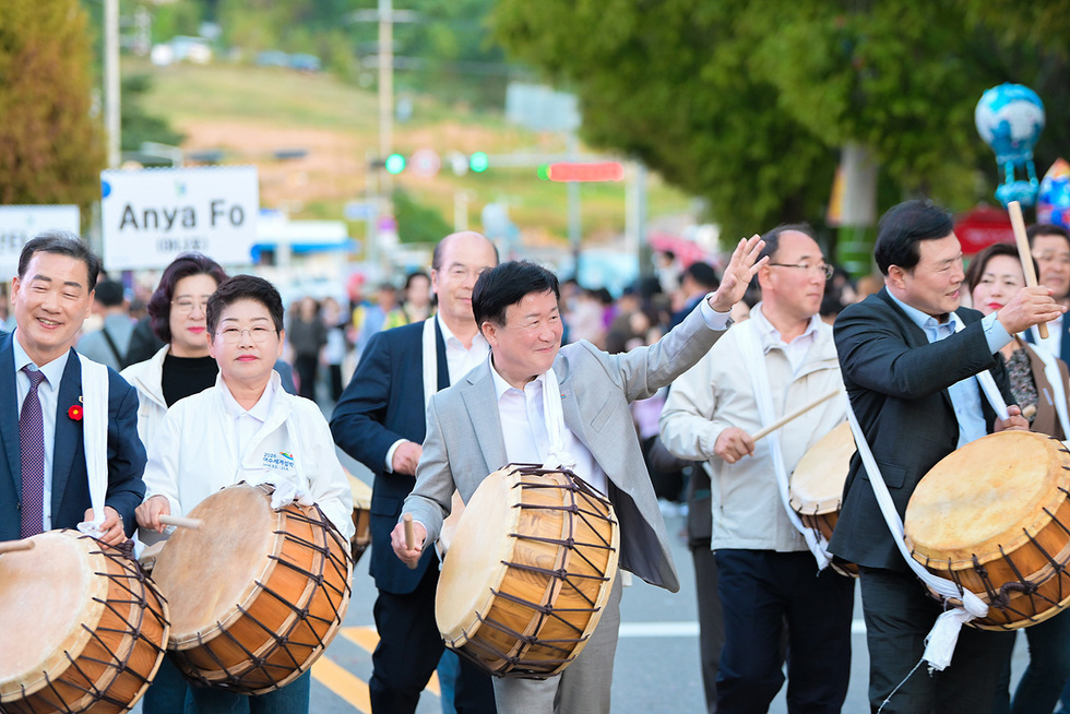 여수동동북축제에서 정기명 여수시장과 관계자들이 북을 치며 행진하고 있는 모습으로, 축제 분위기가 느껴진다.