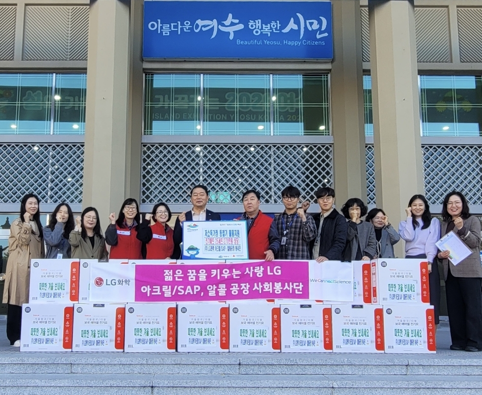 여수시청 앞에서 LG화학 사회봉사단과 관계자들이 전기매트 후원 물품과 함께 기념사진을 찍고 있으며, 앞에 ‘LG 아크릴/SAP·알콜공장 사회봉사단’과 ‘저소득 가정 전기매트 전달식’ 현수막이 놓여 있다