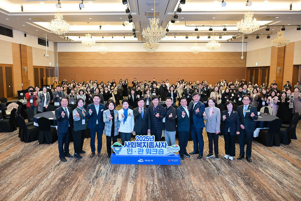 사회복지종사자 민·관 워크숍 참석자들이 넓은 연회장에 모여 단체 기념촬영을 하며 손가락 하트를 들고 있는 모습