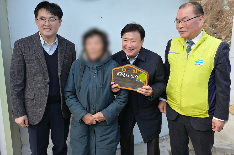 여수시장이 롯데케미칼 관계자들과 함께 화양면 독거 어르신 가정을 방문해 ‘희망하우스 30호’ 현판을 들고 기념 촬영하고 있으며, 어르신과 관계자들이 함께 서 있는 모습