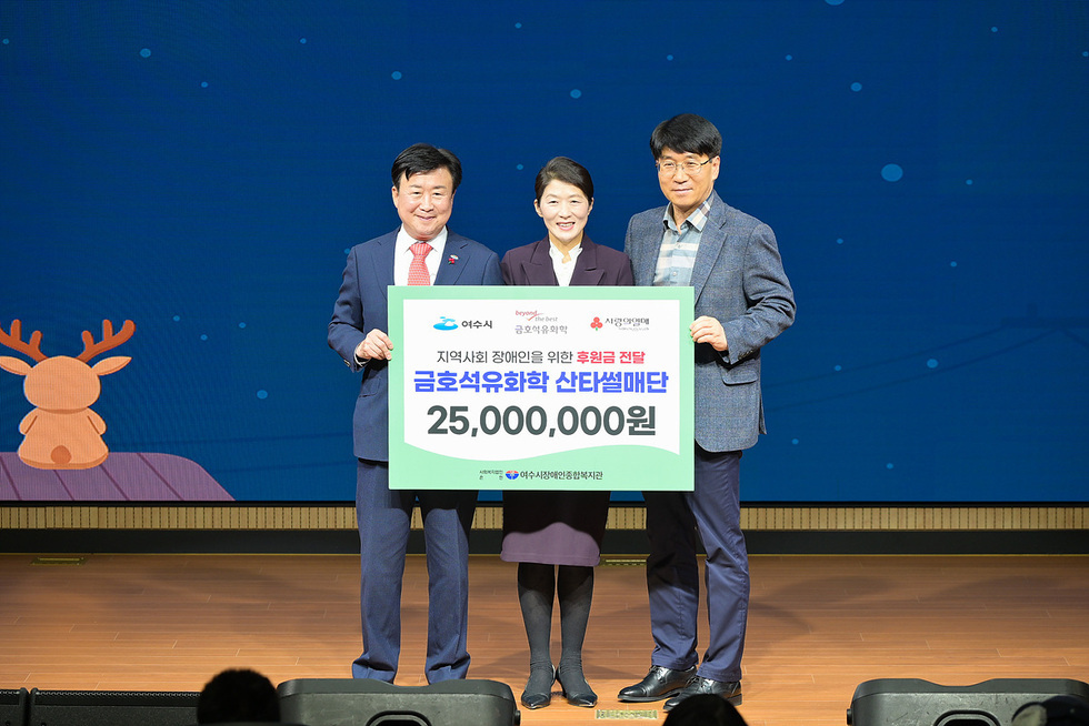 파란색 겨울 밤하늘과 루돌프가 그려진 무대 배경 앞에서, 정장을 입은 여수시장,이승철 전무, 최종순 관장이 ‘지역사회 장애인을 위한 후원금 전달, 금호석유화학 산타썰매단 25,000,000원’이라고 적힌 대형 판넬을 함께 들고 기념 촬영을 하고 있다.