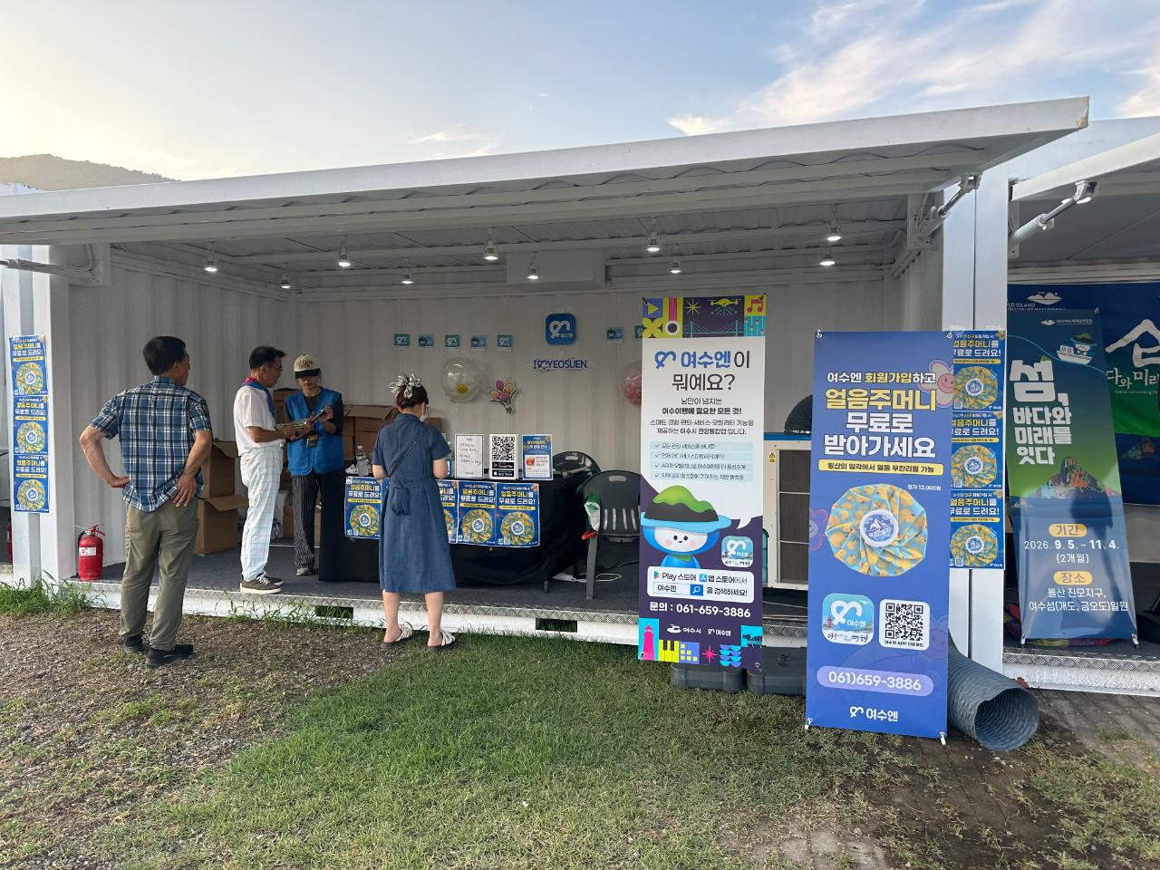 여수에서 얼음주머니를 무료로 제공하는 부스에서 사람들이 대화하고 있는 장면이다.