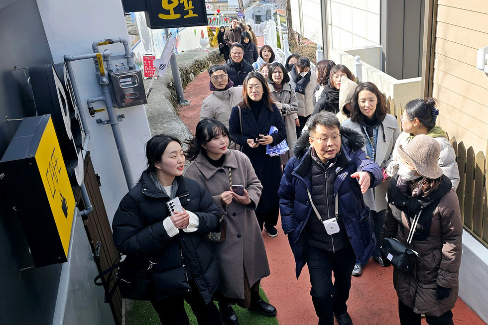여러 명의 사람들이 오포라는 간판이 있는 길을 걷고 있으며, 한 남성이 앞에서 설명하고 있다.