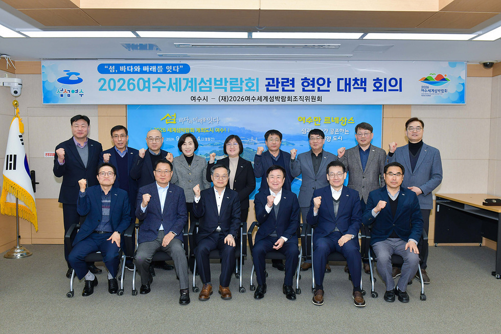 여수시에서 2026여수세계섬박람회 관련 협안 대책 회의가 진행되고 있으며, 참석자들이 주먹을 쥐고 포즈를 취하고 있다.