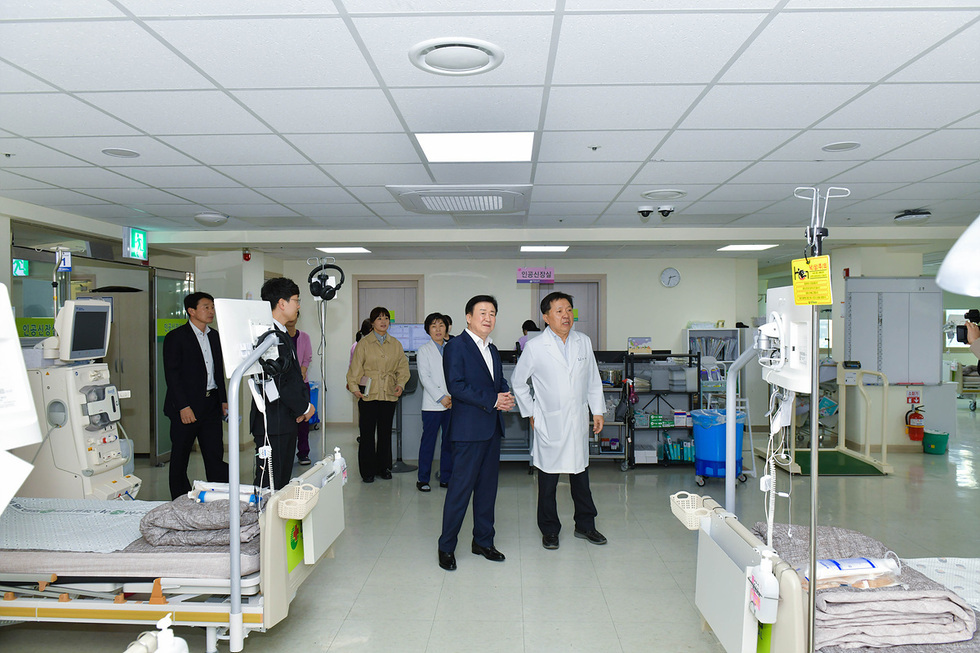 의료진과 관계자들이 병원 내부에서 대화하며 둘러보고 있는 장면이다