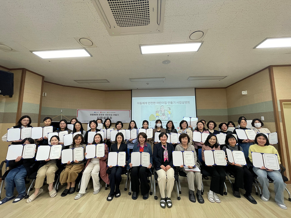여성들이 아동학대 예방을 위한 안전한 어린이집 만들기 사업설명회에서 수료증을 들고 기념사진을 찍고 있다.