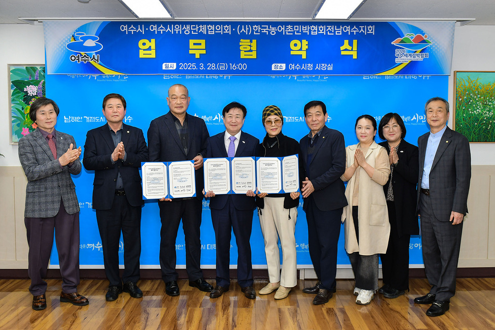 여수시청 시장실에서 여수시와 여러 단체가 업무협약을 체결하는 장면으로, 참석자들이 협약서를 들고 있다.