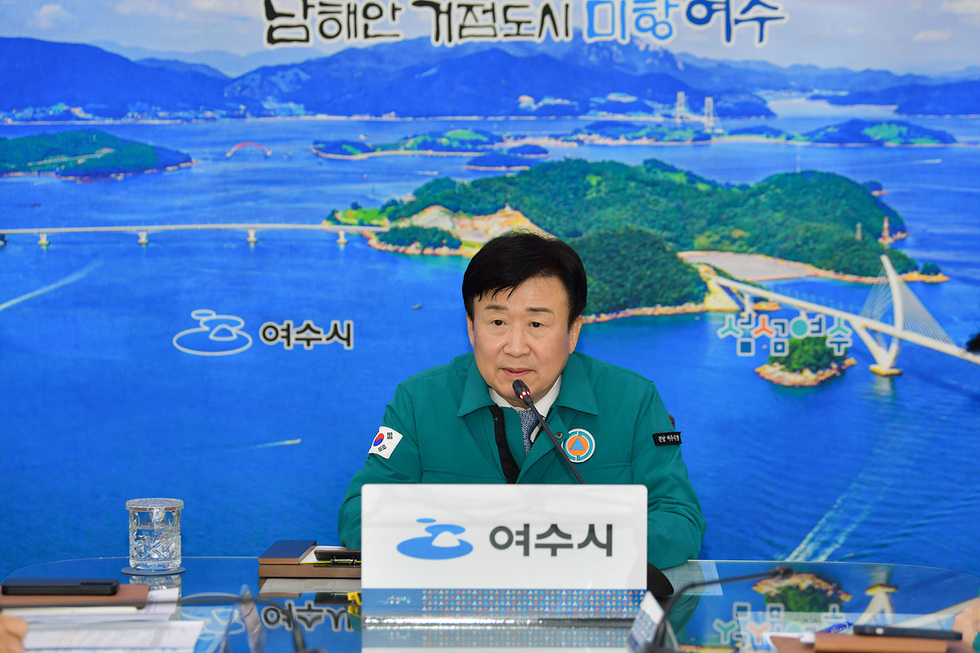 여수시청에서 한 관계자가 회의 중이다. 배경에는 여수의 아름다운 바다와 섬들이 보인다.