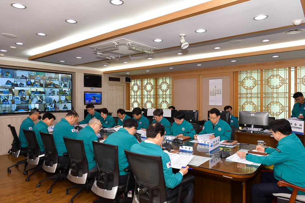 재난안전대책본부 회의에서 여러 사람이 회의에 참석하고 있으며, 화면에는 화상회의 참가자들이 보인다.