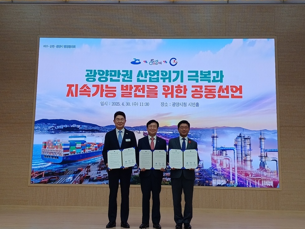 광양시청 시민홀에서 광양만권 산업위기 극복과 지속가능 발전을 위한 공동선언을 하는 장면으로, 세 명의 남성이 선언문을 들고 서 있다.