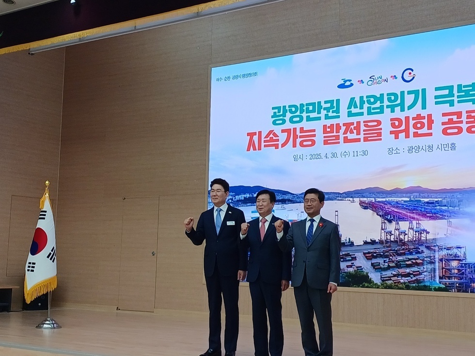 광양시청 시민홀에서 광양만권 산업위기 극복을 위한 공론화 행사에 참석한 세 명의 남성이 포즈를 취하고 있다.