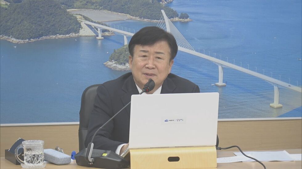 여수시에서 시청각 회의 중인 남성이 노트북 앞에 앉아 있다. 배경에는 바다와 다리가 보인다.