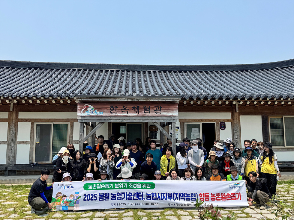 한옥 체험관 앞에서 농촌 일손 돕기 행사에 참여한 사람들 50여명이 단체 사진을 찍고 있다.