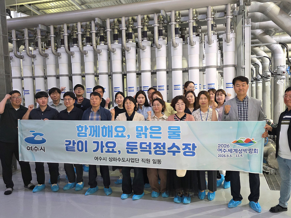 여수시 상하수도사업단 직원들이 둔덕정수장에서 함께 기념사진을 찍고 있으며, 배경에는 정수시설이 보인다.