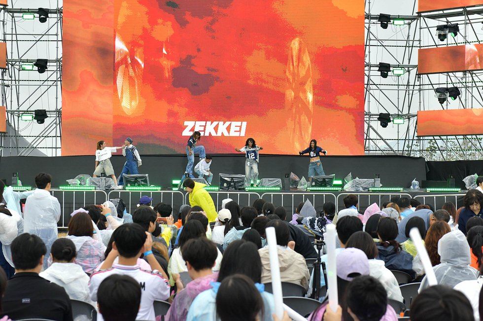 무대에서 공연 중인 댄서들이 있으며, 관객들이 공연을 관람하고 있다. 배경에는 ZEKKAI라는 글자가 보인다.