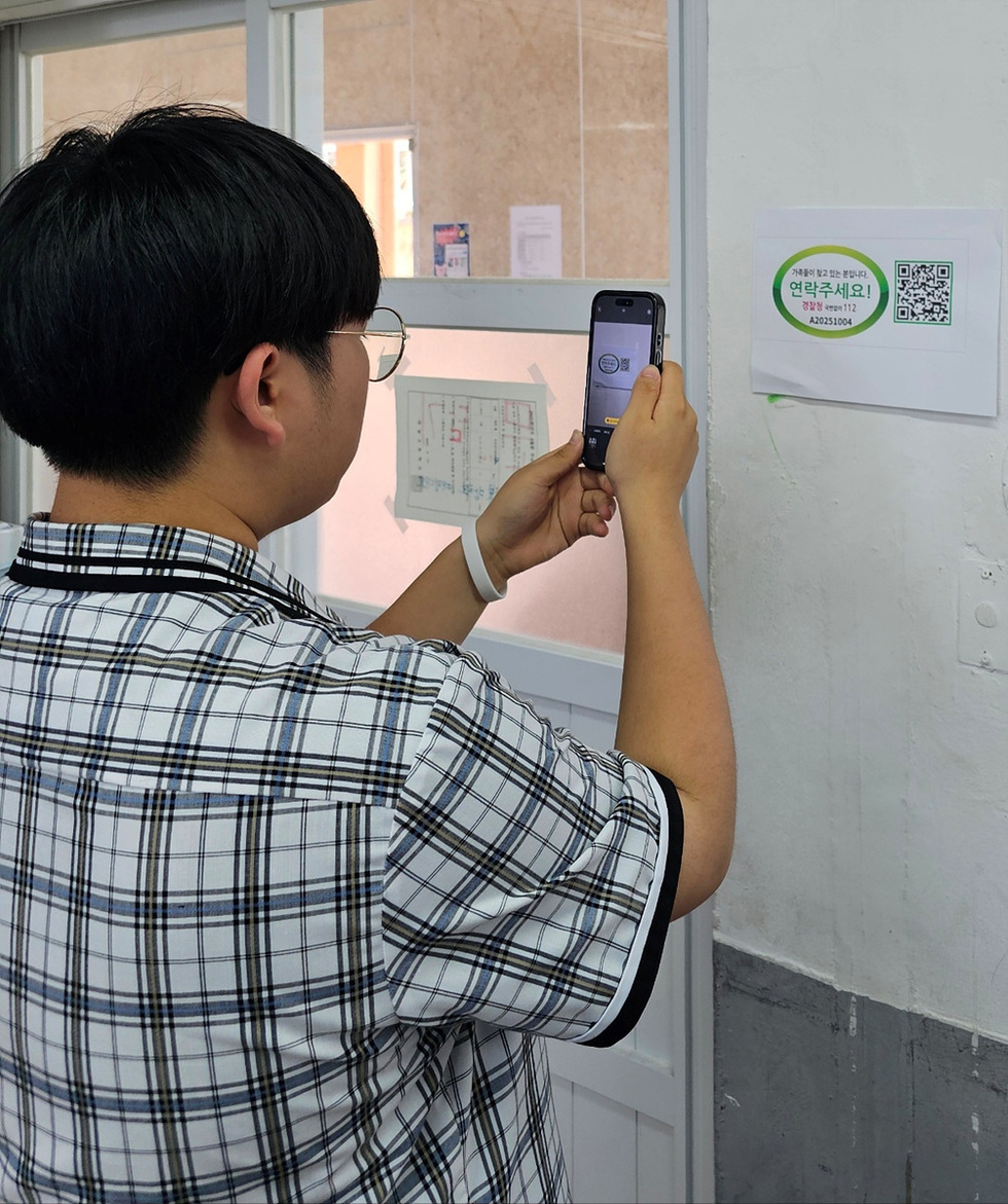 한 남성이 벽에 붙어 있는 연락처 안내문을 스마트폰으로 촬영하고 있다.