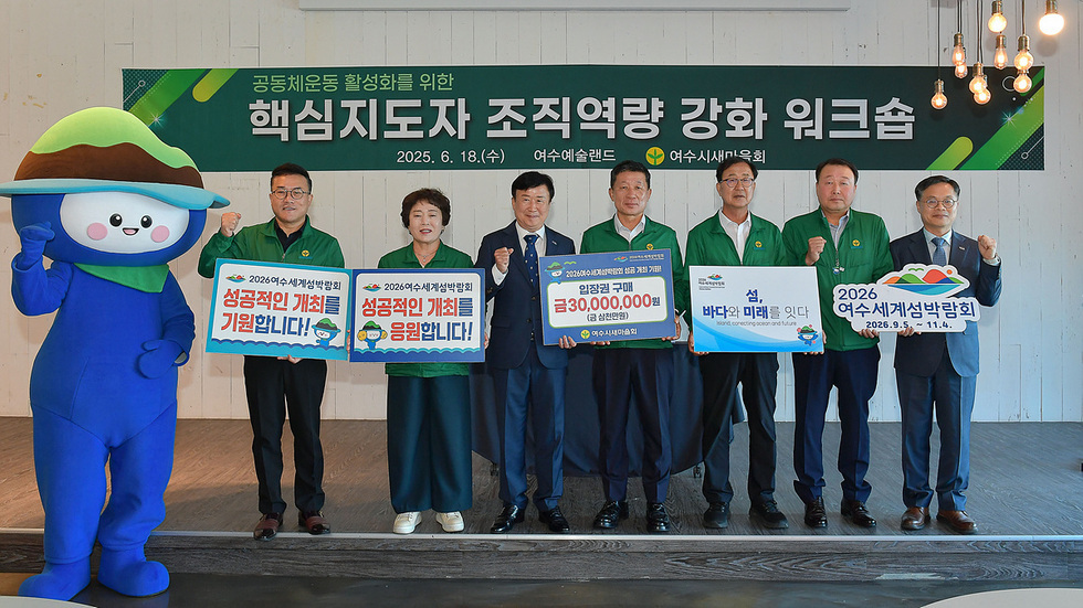 여수에서 열린 공동체운동 활성화를 위한 핵심지도자 조직역량 강화 워크숍에서 여러 관계자들이 기념사진을 찍고 있다. 참석자들은 2026여수세계섬박람회의 성공적인 개최를 기원하는 현수막을 들고 있다.