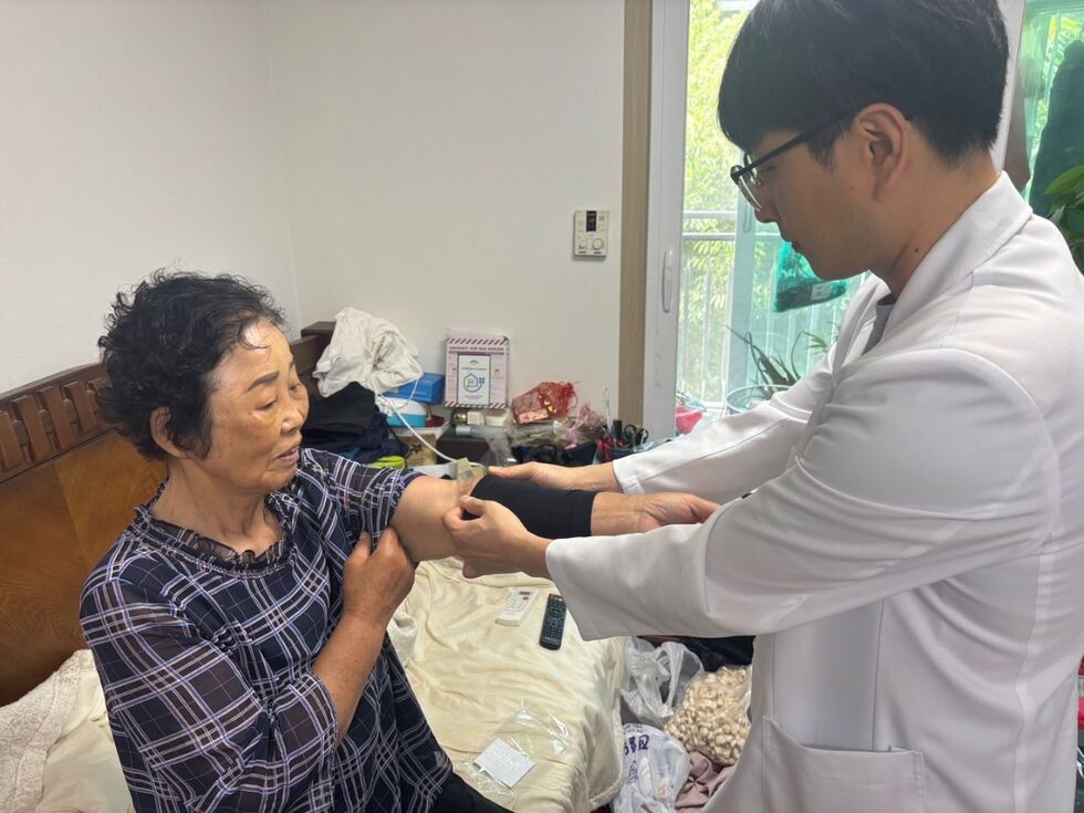 의사가 고령 여성의 혈압을 측정하며 건강 상태를 살피는 모습