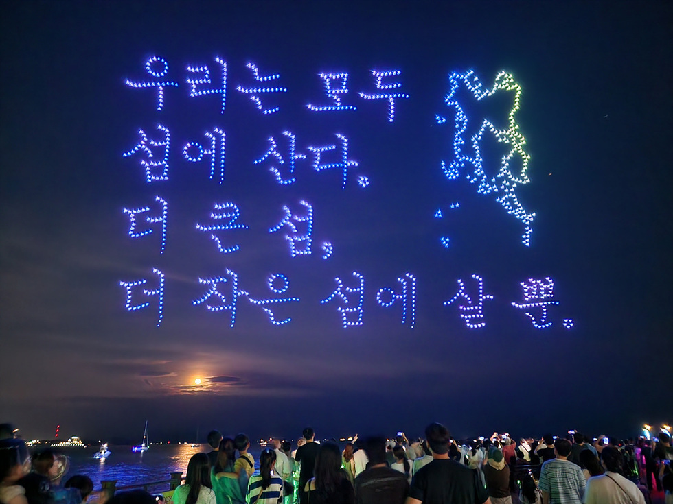 여수 밤하늘에 1,000대 드론으로 구현된 라이트쇼, ‘우리는 모두 섬에 산다. 더 큰 섬, 더 작은 섬에 살 뿐.’이라는 문구와 섬 모양이 빛으로 수놓인 장면