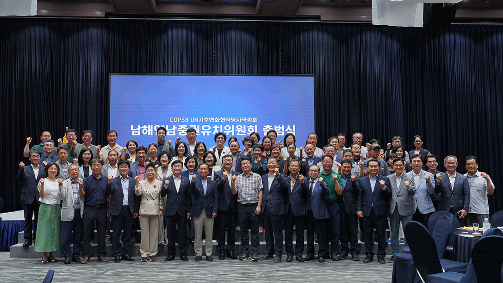 남해안남중권유치위원회 출범식에서 참석자들이 단체 사진을 찍고 있다. 배경에는 COP33 UN기후변화협약사무국 관련 문구가 보인다.