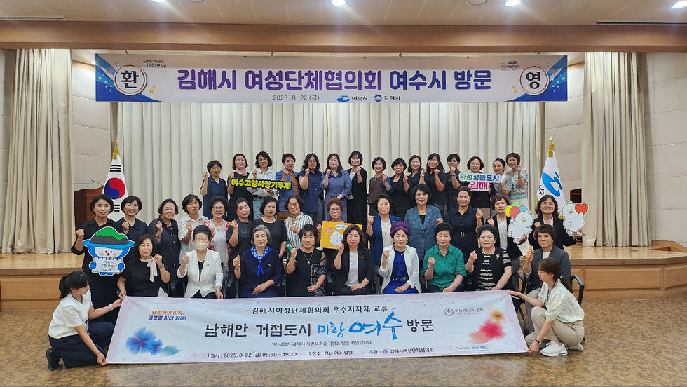 김해시 여성단체협의회가 여수시를 방문하여 기념사진을 촬영하고 있다. 참석자들은 다양한 표정을 지으며 손을 흔들고 있다.