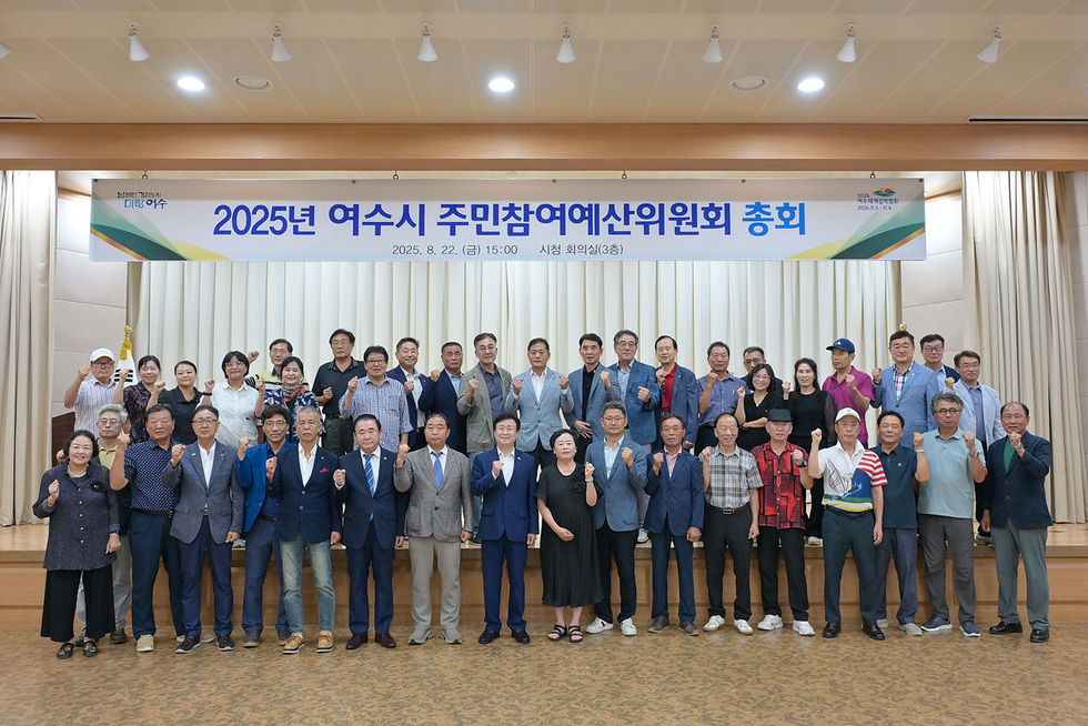 여수시 주민참여예산위원회 총회에서 참석자들이 단체 사진을 찍고 있다. 회의실에서 여러 사람들이 모여 포즈를 취하고 있다.