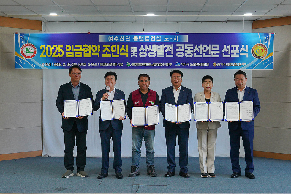 여수산단에서 2025 임금협약 조인식 및 상생발전 공동선언문 선포식이 진행되고 있으며, 여러 관계자들이 서명된 문서를 들고 있다.