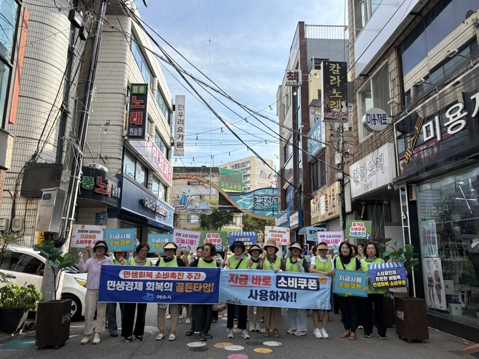 여수시에서 소비촉진을 위한 캠페인에 참여한 사람들이 소비쿠폰 사용을 촉구하며 행진하고 있다.