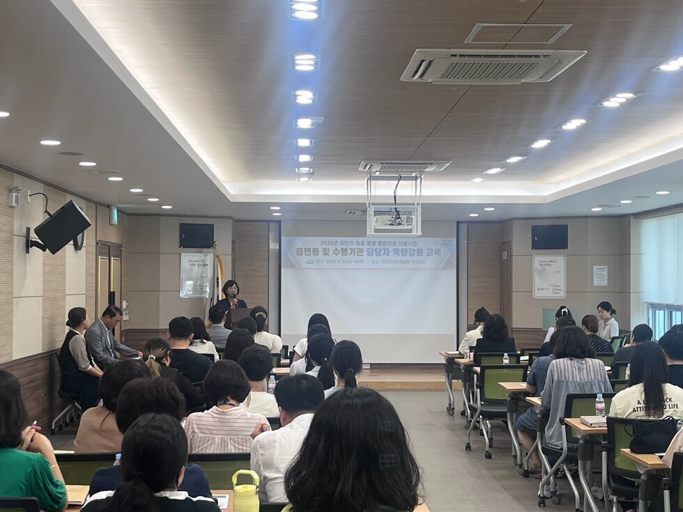 강의 중인 여성 강사와 청중이 있는 교육 현장으로 응급 및 수술기관 담당자 역량강화 교육이 진행되고 있다.